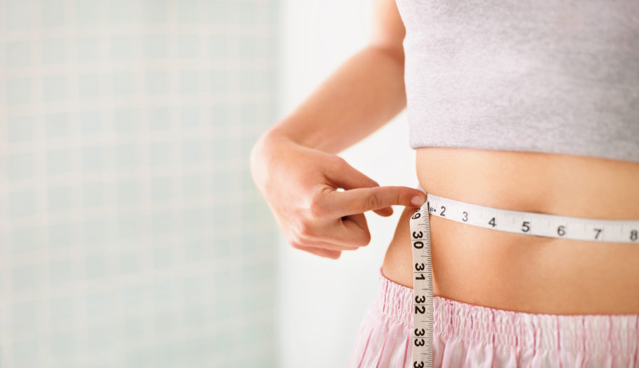 Detail view of a beautiful woman measuring her waist