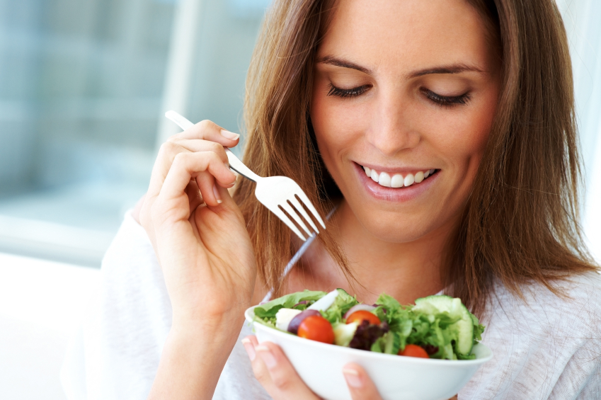 Close-up of young happy woman eating salad