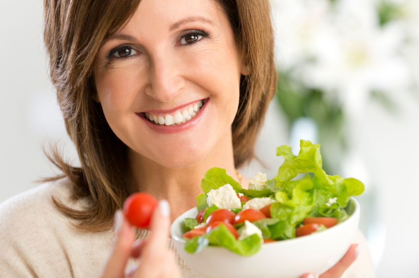 Happy mature woman holding a salad
