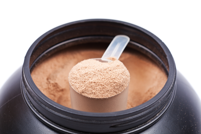 Scoop of chocolate whey isolate protein in a black plastick cont