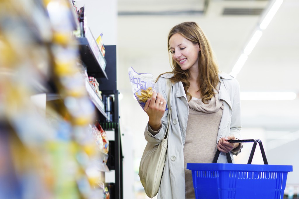 Beautiful young woman shopping in a grocery store/supermarket (color toned image)