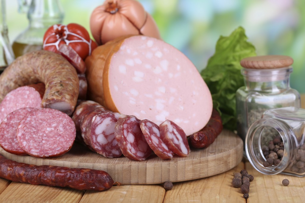 Different sausages on wooden table on natural background