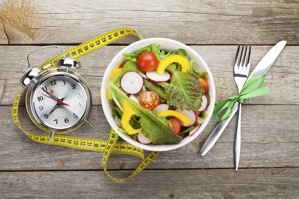Fresh healthy salad and measuring tape on wooden table. Healthy food
