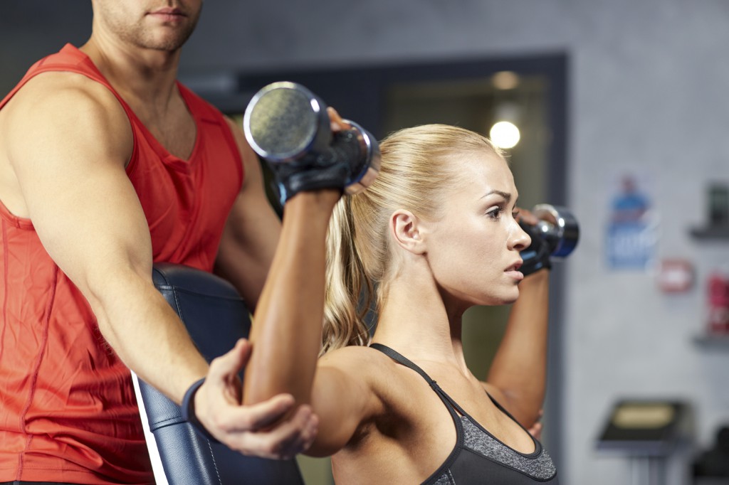 sport, fitness, bodybuilding, lifestyle and people concept - man and woman with dumbbells flexing muscles in gym