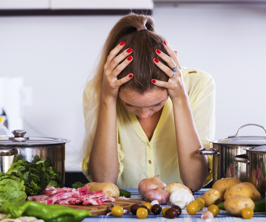 Fatigued housewife with meat and vegetables at kitchen table