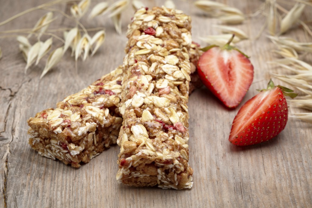 Granola bar and strawberries on wooden background