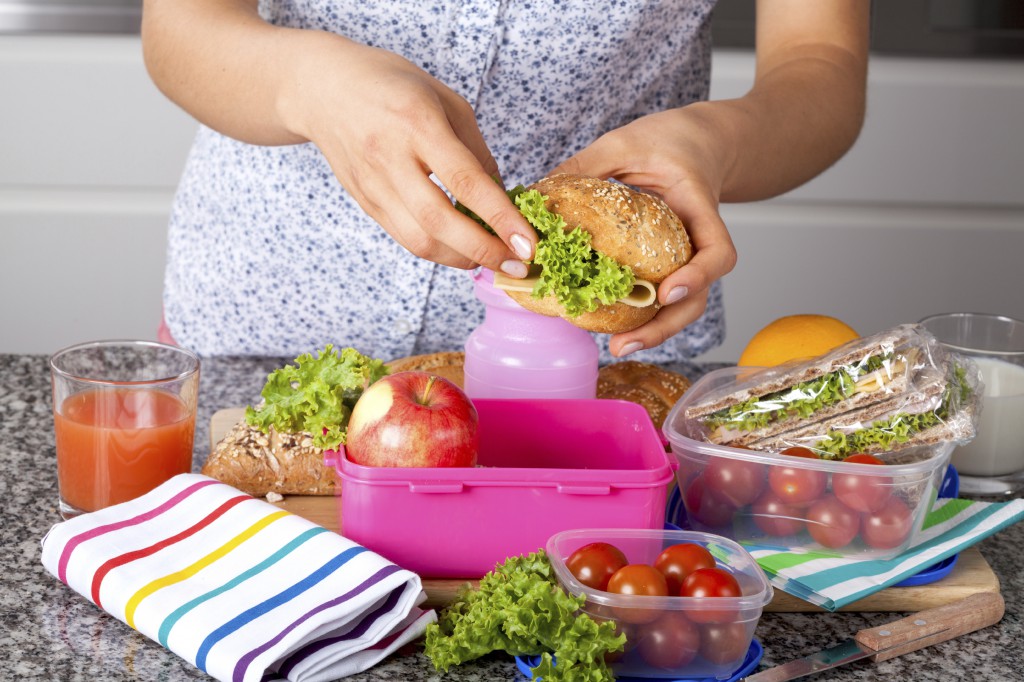 Woman preparing delicious sandwich with cheese and green salad