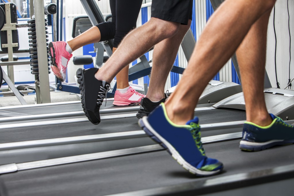 Group of legs wearing sneakers running on treadmill at sport gym.