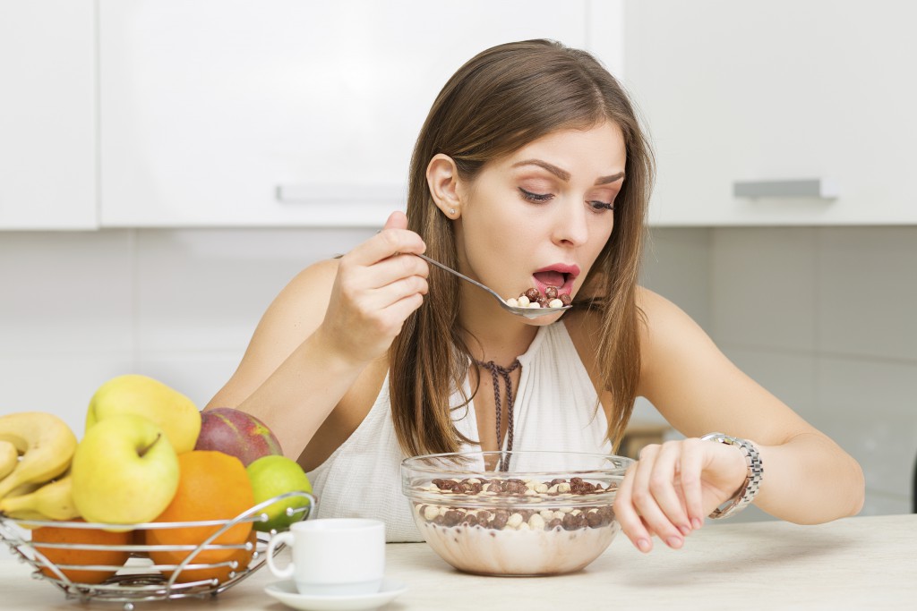 Beautiful woman having coffee, fruits and oatmeal for breakfast