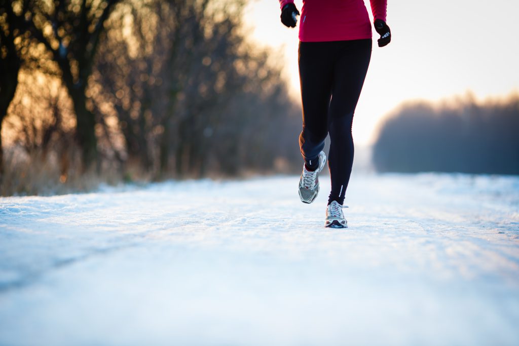 Winter running - Young woman running cross-country outdoors on a cold winter day (motion blurred image, color toned image)