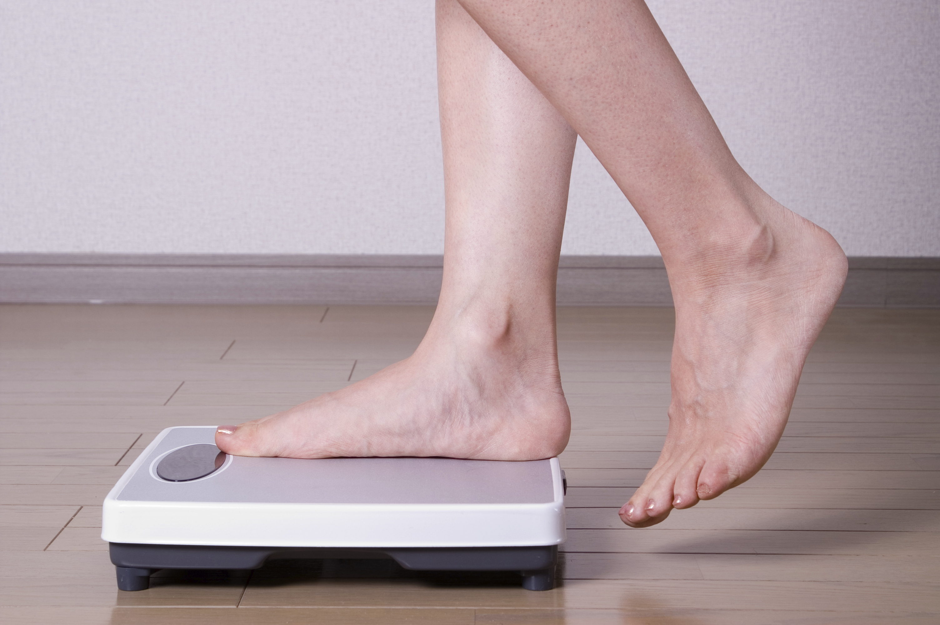 Woman stepping on scales and weighing herself
