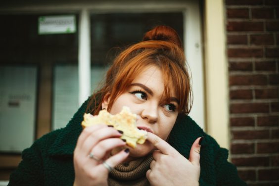 Une femme mange son sandwich sur sa galerie